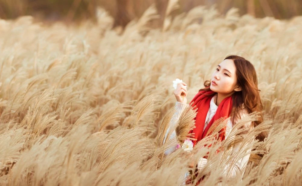 A photo of a woman standing with tall grasses