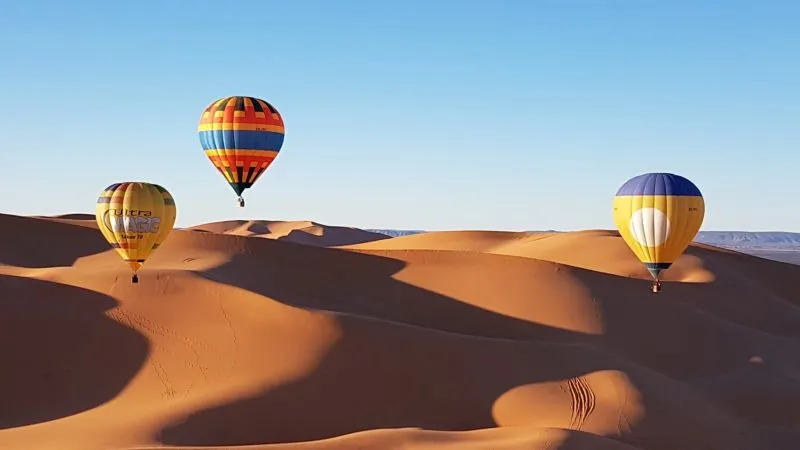 A photo of three hot air balloons overlooking the desert