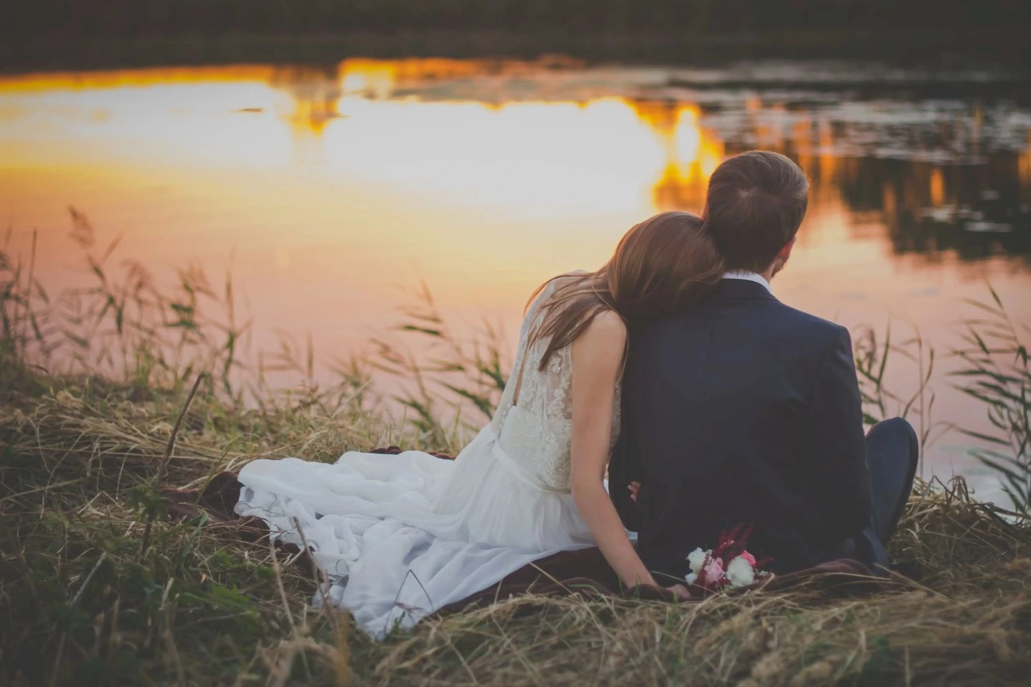 A couple in their wedding attire observing a lake